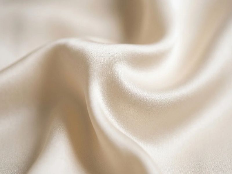 Close-up texture of high-quality mulberry silk fabric showing momme density and soft sheen.
